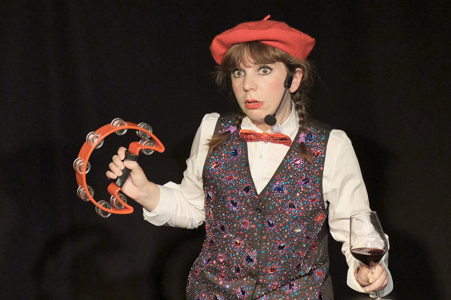 Anna Lou Larkin, with red beret and bow tie, tambourine and a glass of red wine, in 'Le Wine Club'