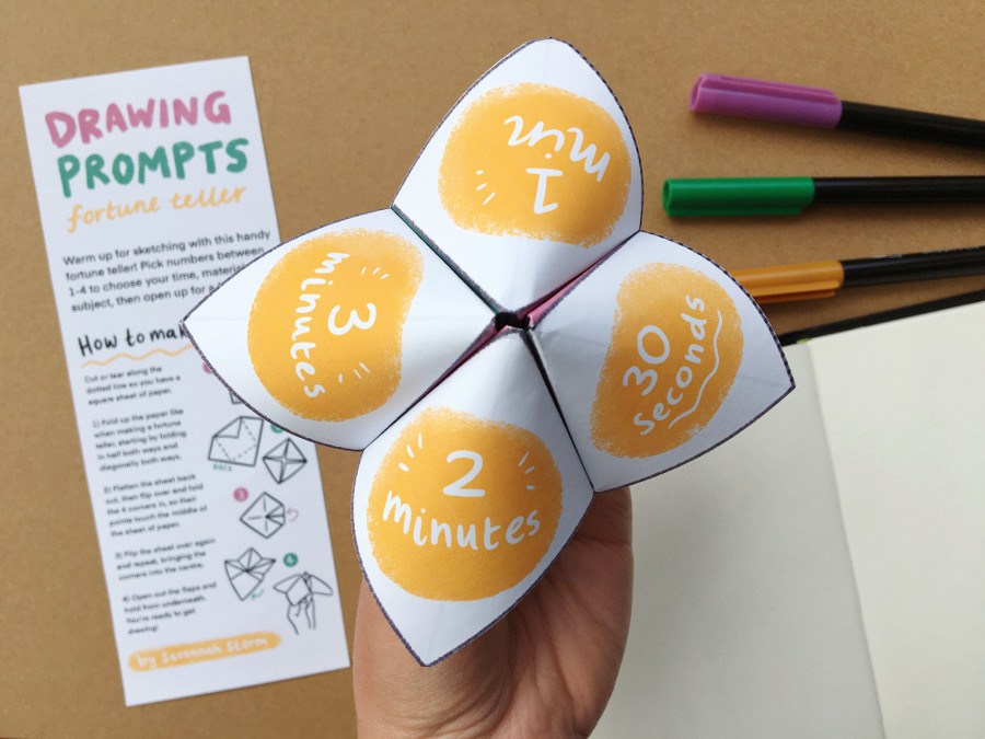 A hand holds up a printed paper fortune teller, with yellow circles on the outside.