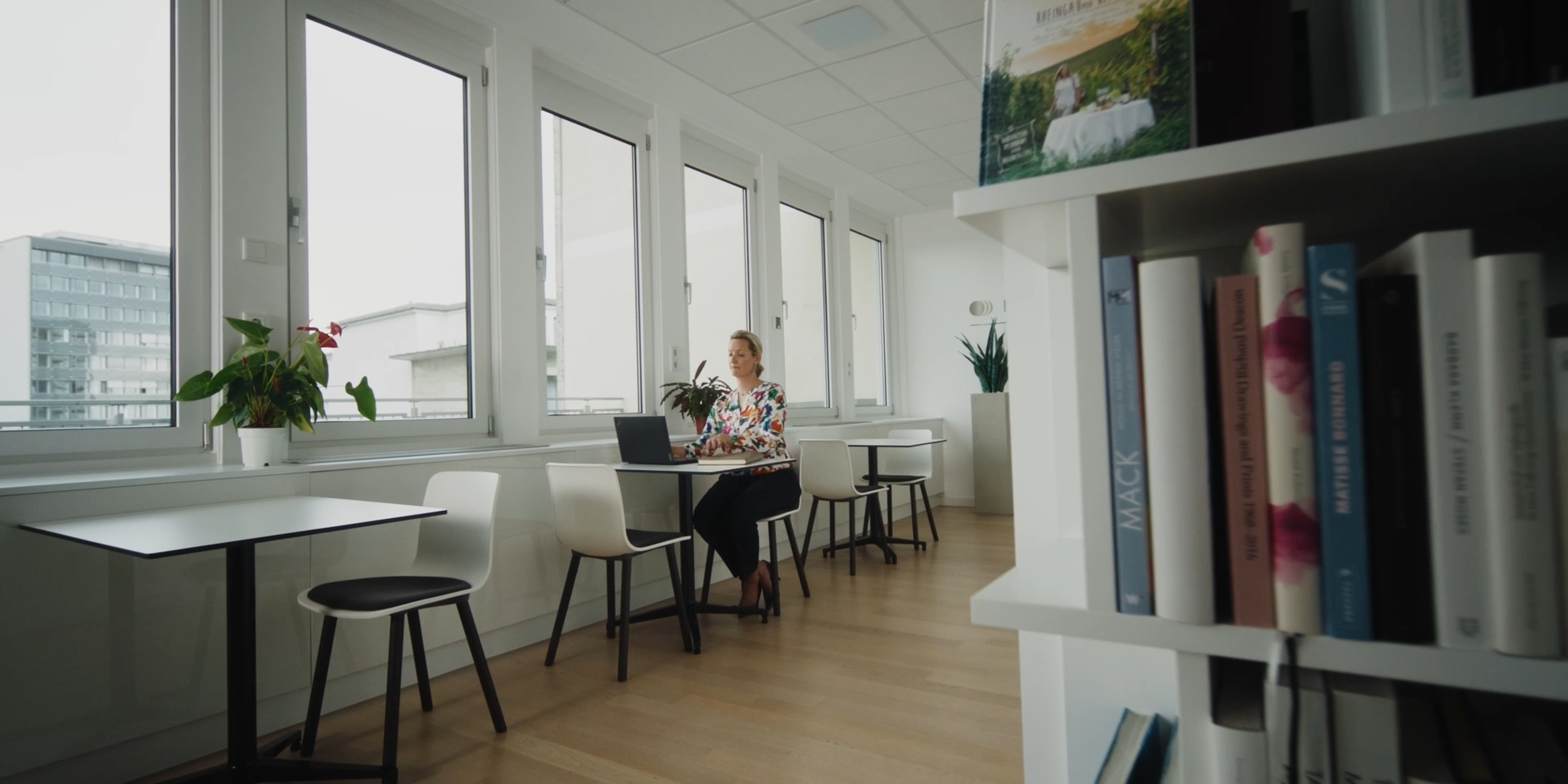 Woman working at a laptop beside the lounge windows