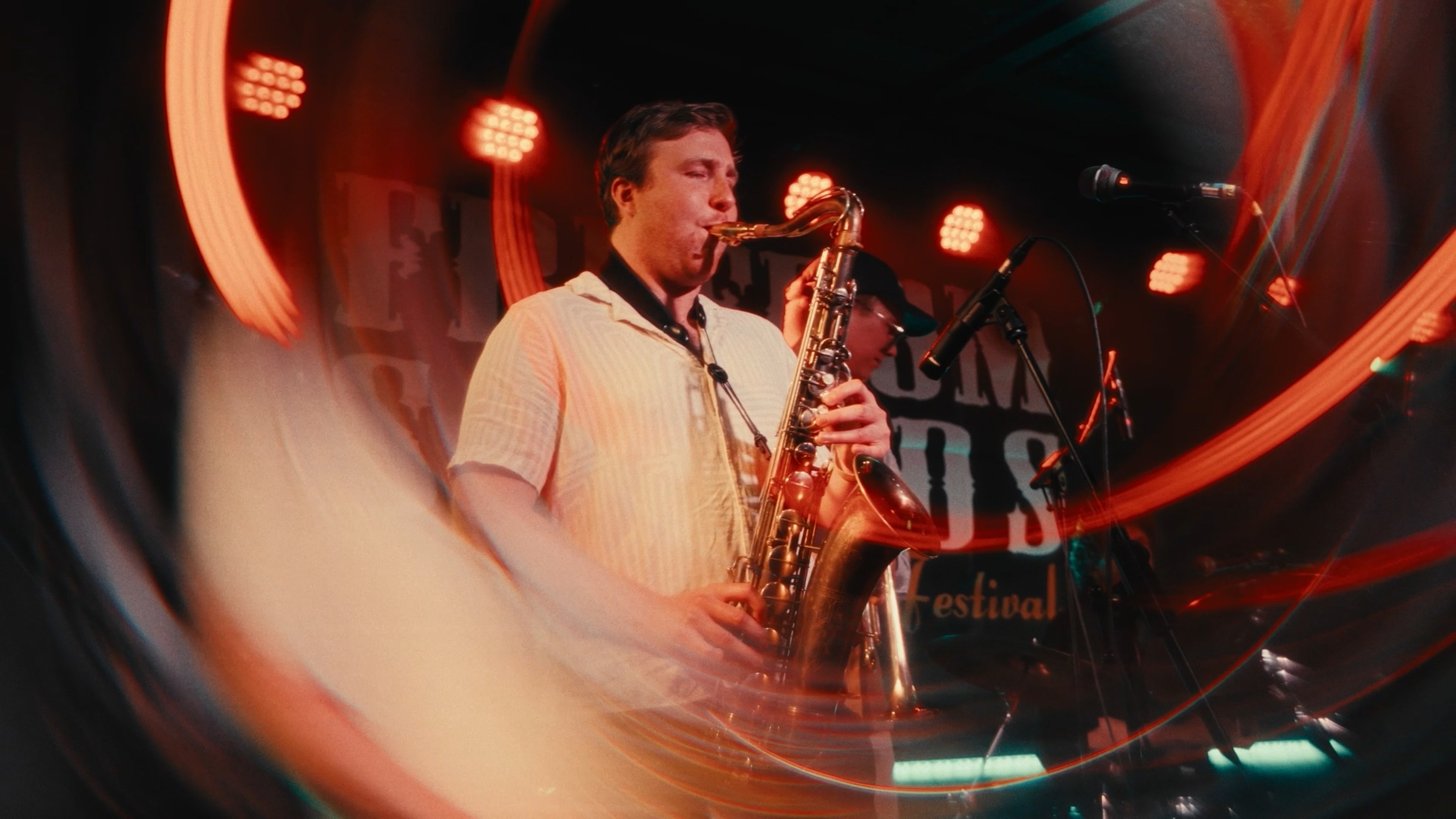 Saxophonist performing in red light with curved foreground reflections