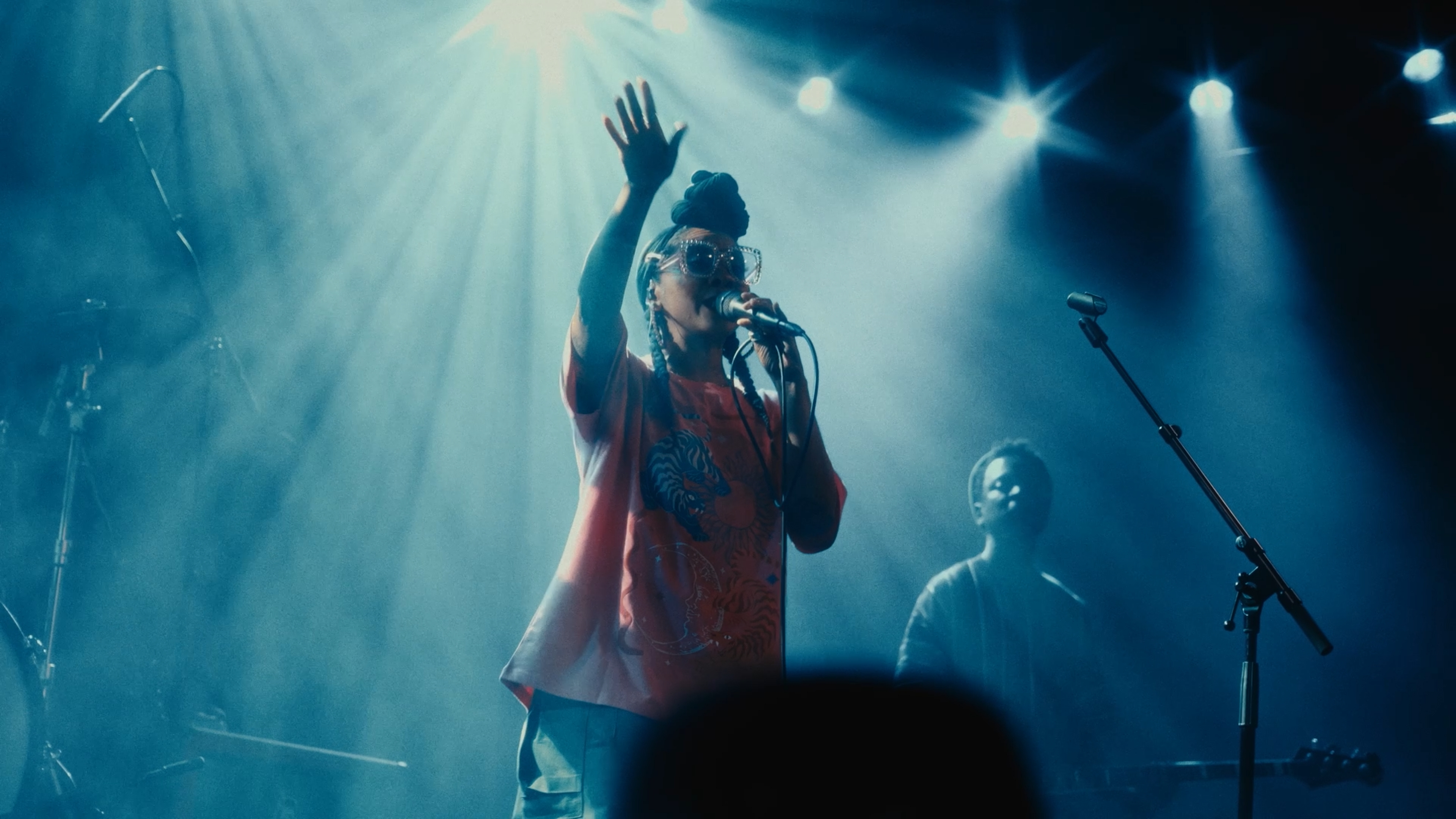 Singer raising her hand beneath blue stage lights
