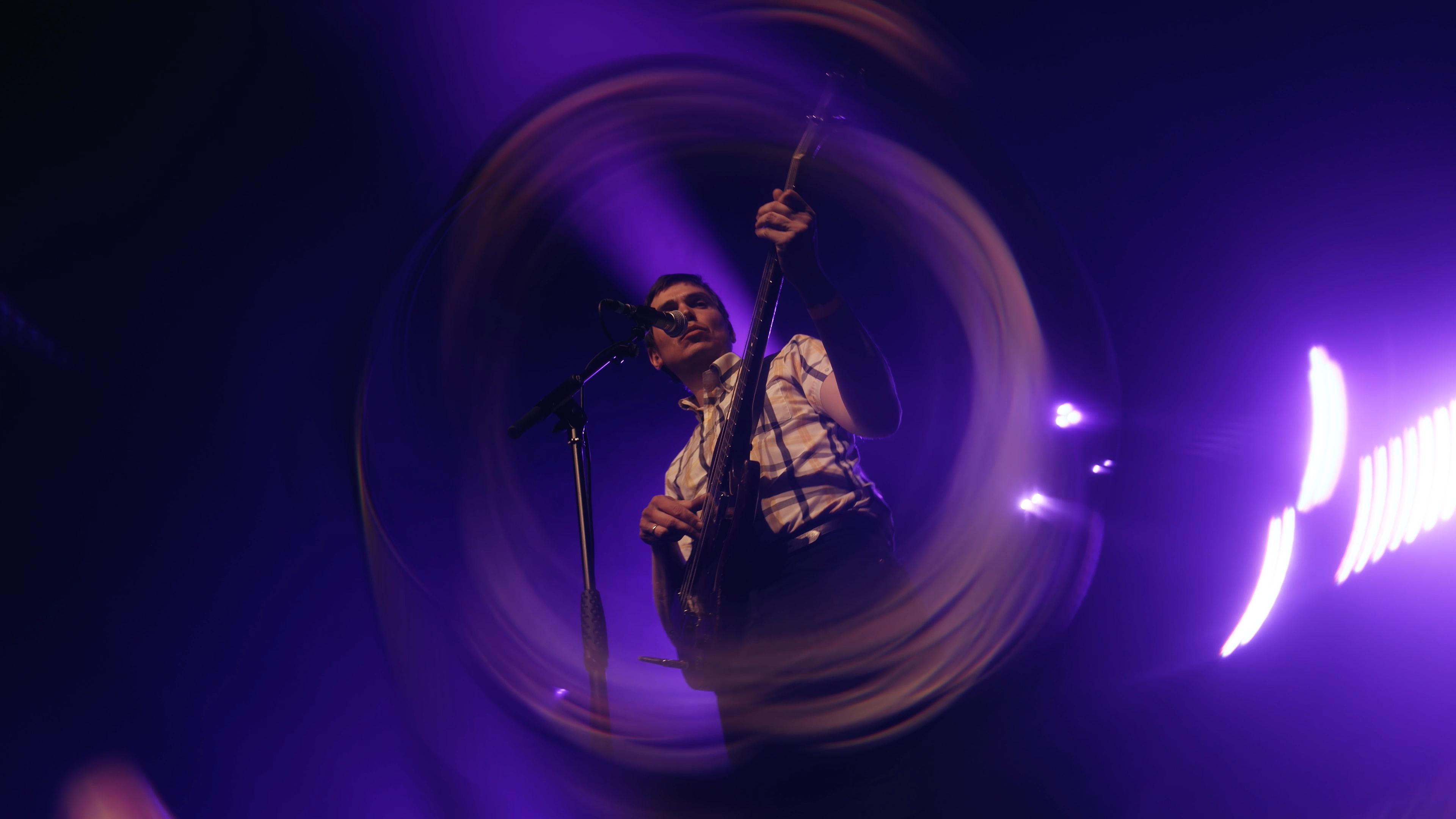 Guitarist seen through a circular lens effect in purple light